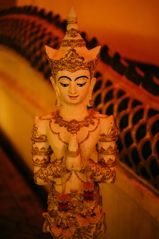 buddha statue sitting in front of a golden handrail