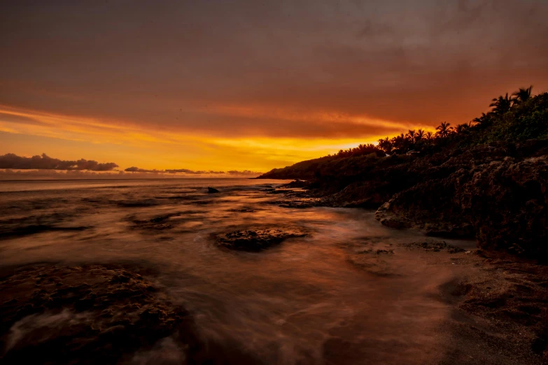 an island is in the water and the sun is setting