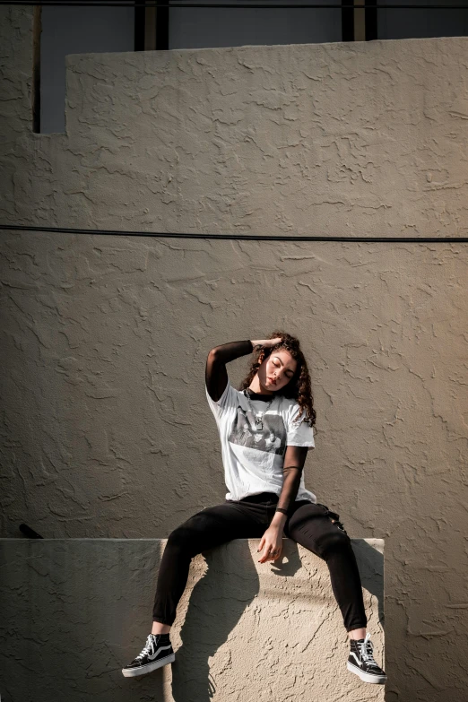 the man is sitting against the wall posing for a picture