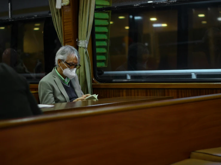 the man is sitting on a train reading his phone