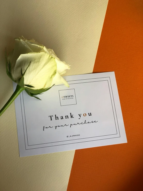 a small card and a white flower on an orange counter