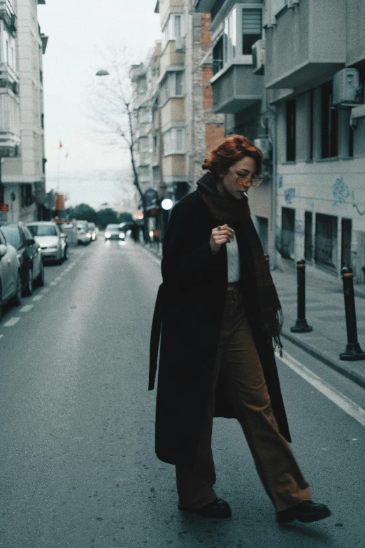 a woman walking down a street while wearing an overcoat