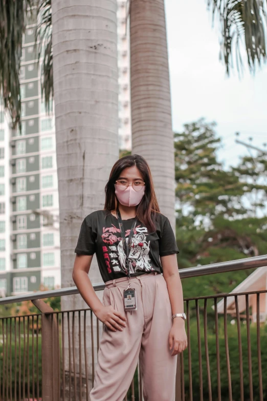 a woman wearing a mask standing next to two palm trees