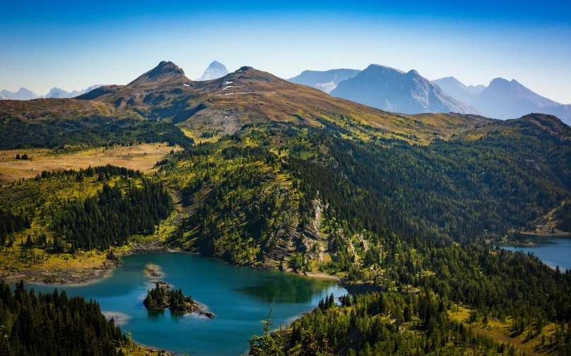 an airplane view of a mountain range with a lake in the foreground