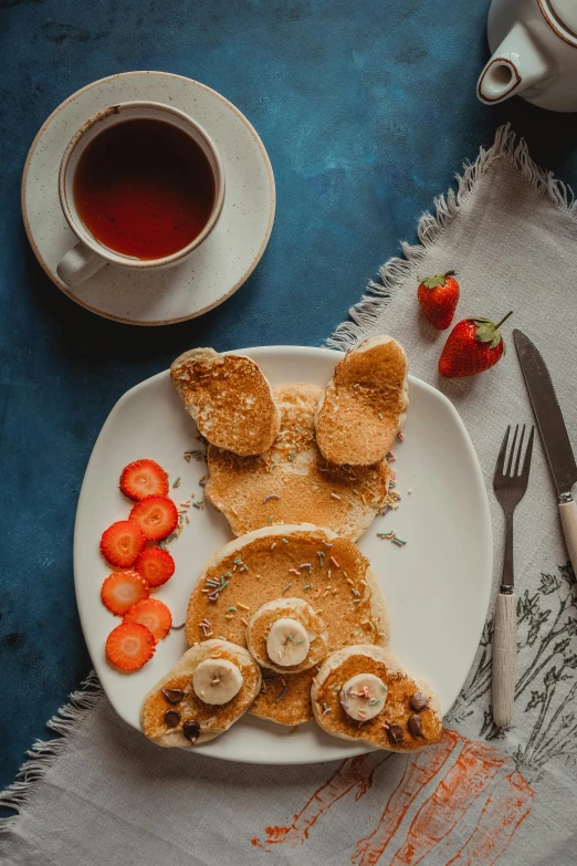 plate of food with meat and vegetable in it next to mug of tea