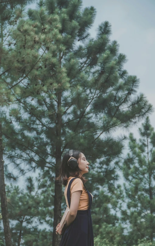 the girl stands by the tall trees