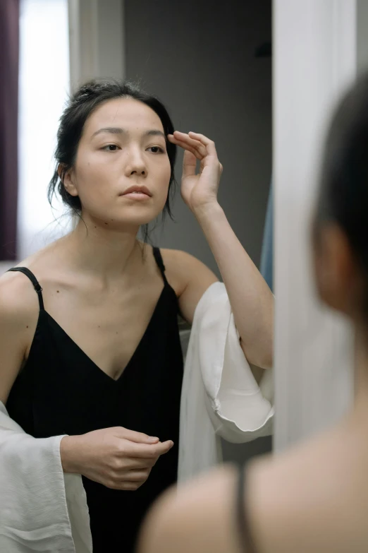 a woman is holding a towel over her hair looking in the mirror