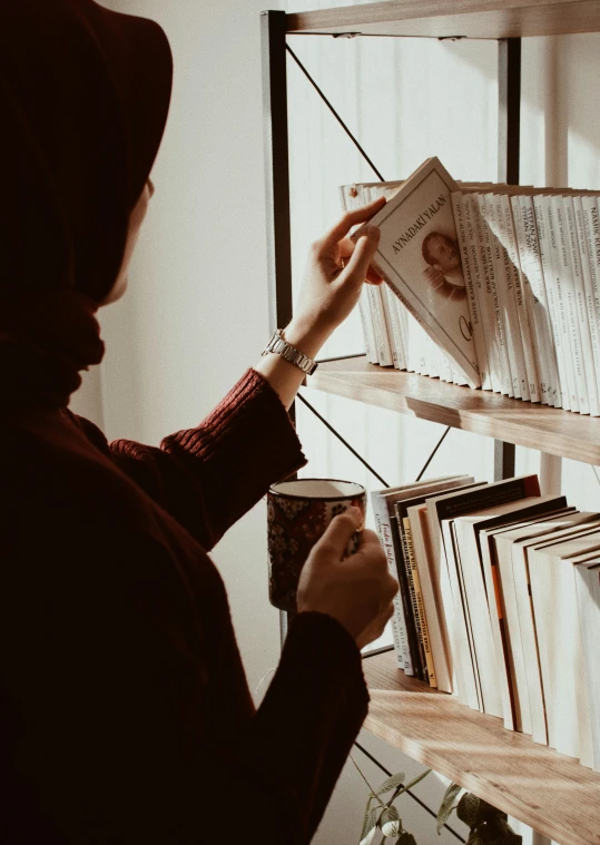 the person is writing on the book shelf