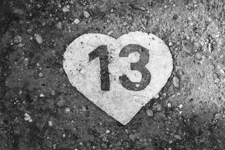 a cement heart on the pavement with the number thirteen thirteen printed into it