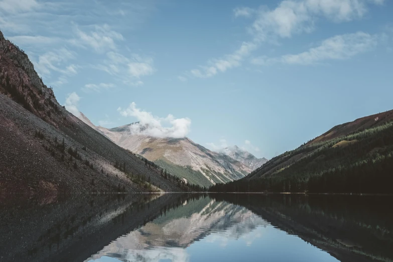 a lake is surrounded by the mountains and blue sky