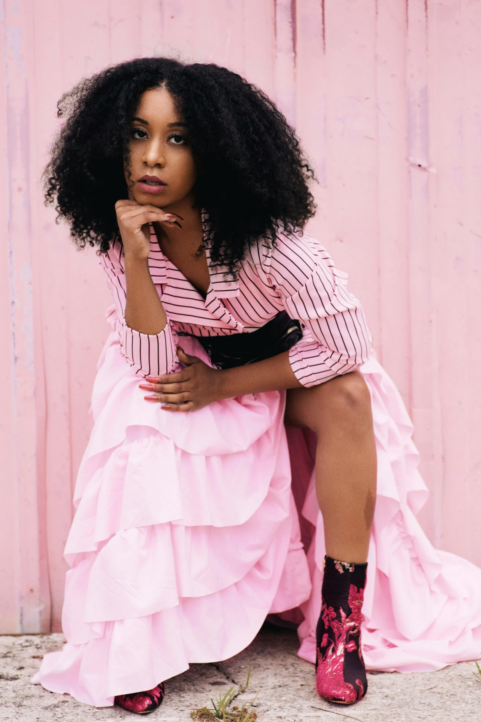 a woman sits in a pink dress on the ground