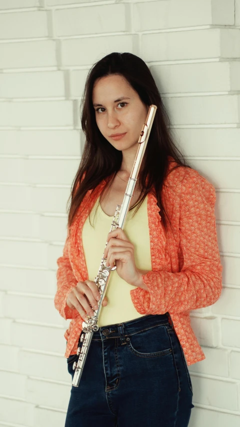 a woman with a flute leaning against a wall