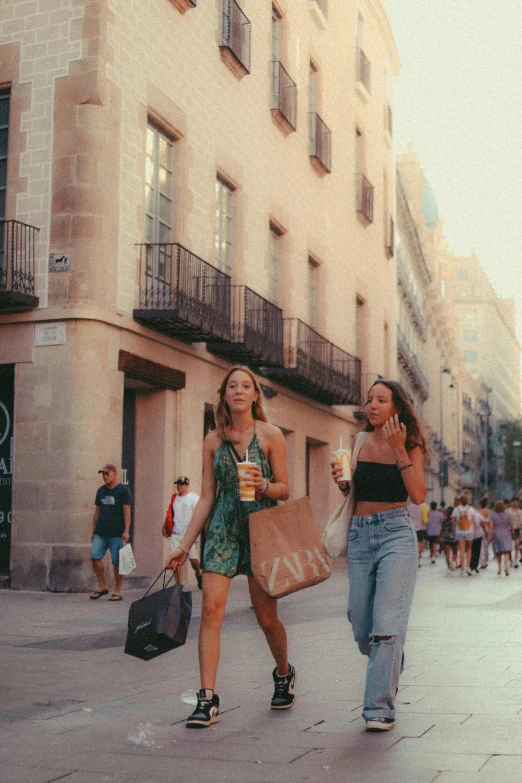 two young women walking down the street with bags of food