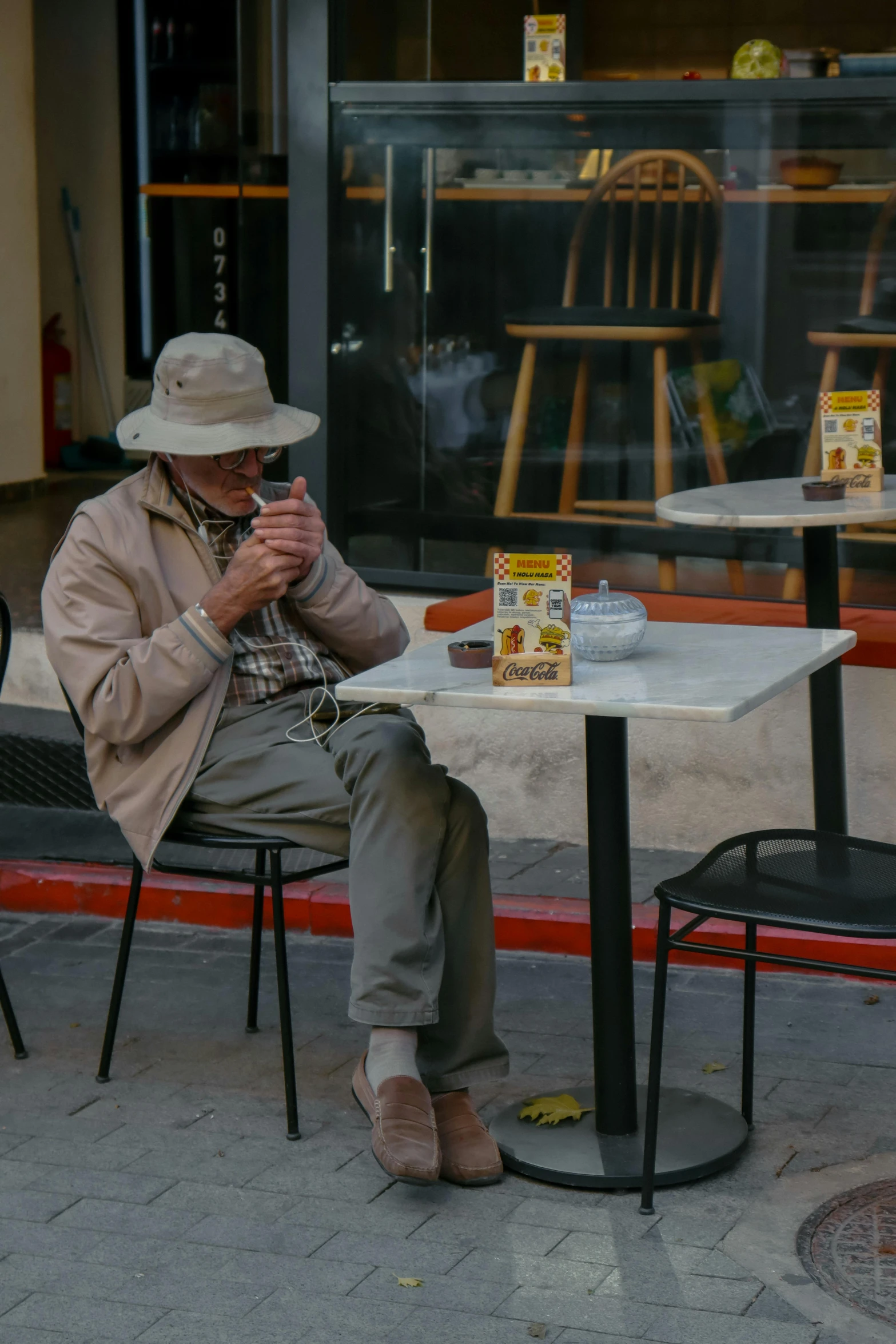 a man sits at an outdoor table and uses his cell phone