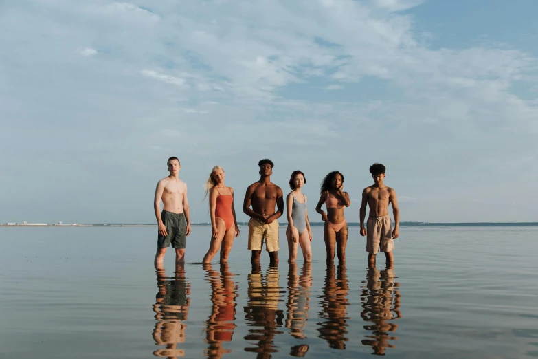 four people are standing in the water by a pier