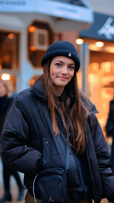 a woman in black coat and beanie outside of a store