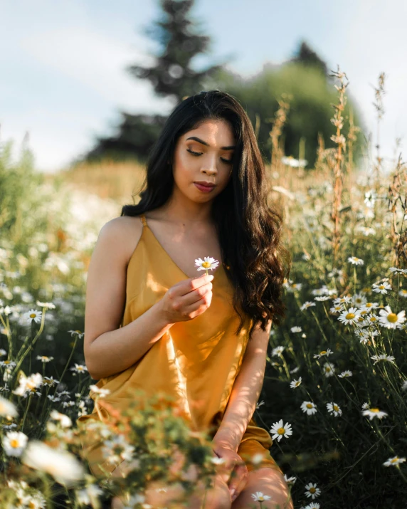 a woman in an orange dress stands among white flowers