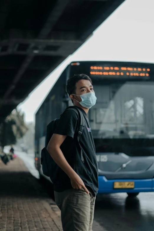 a man in a protective mask waits for the bus