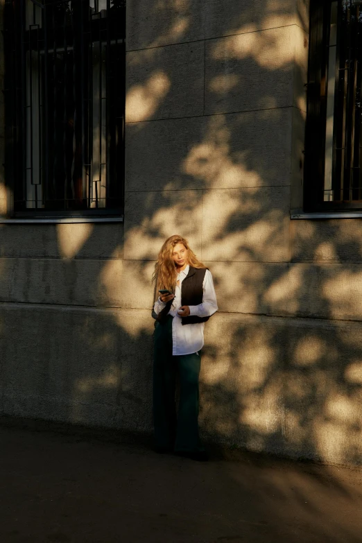 the woman is standing near a building with the back to her purse