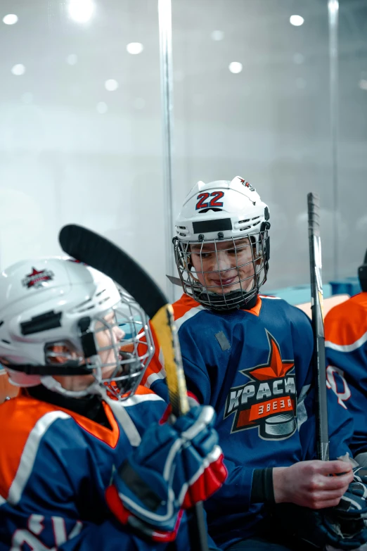 several lacrosse players wearing helmets holding sticks in a hockey arena