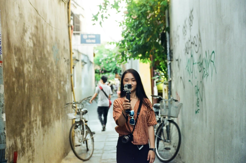 the girl with a camera takes a po of another person on a city street