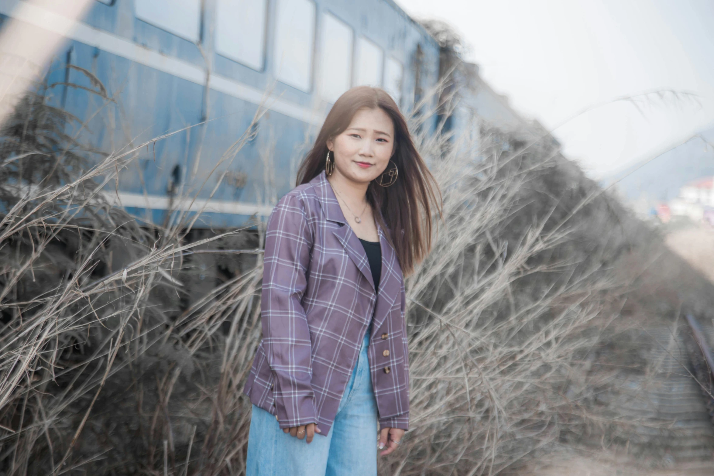 a girl wearing an oversize jacket in front of a train