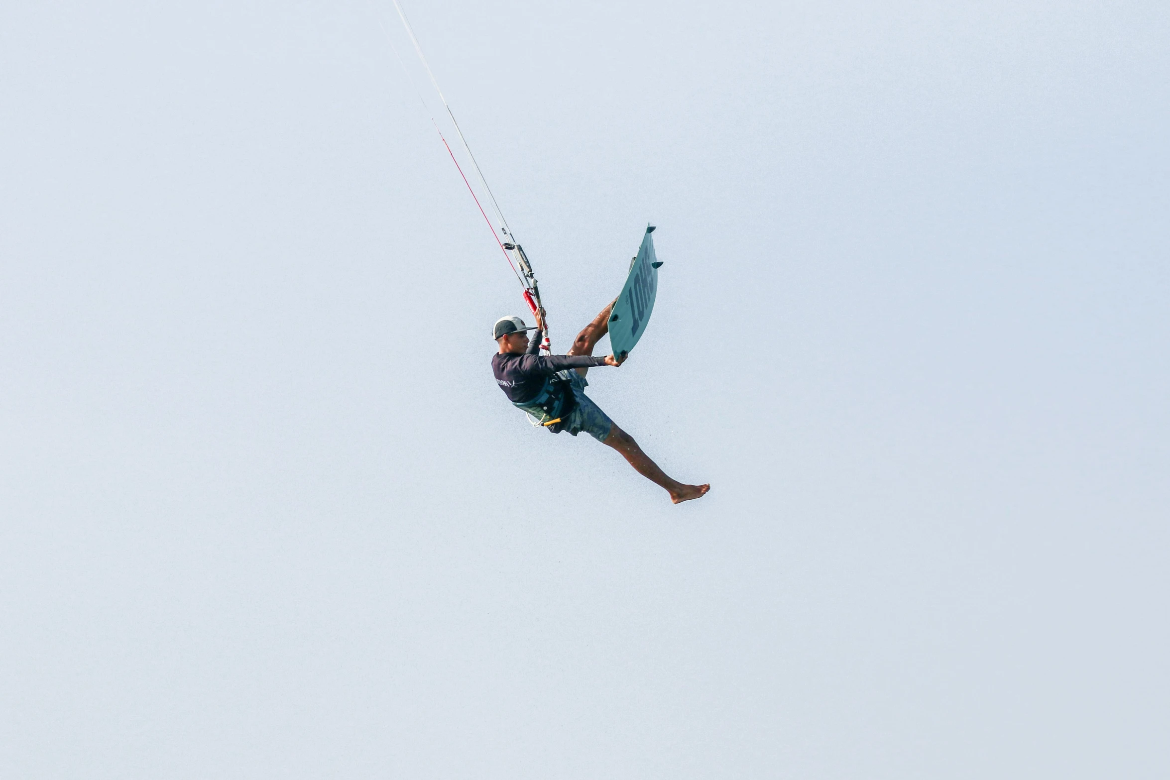 the parasail player in the blue water is suspended from the line