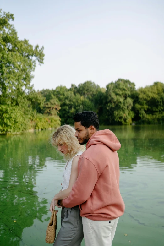 a man and woman standing on the shore of a body of water