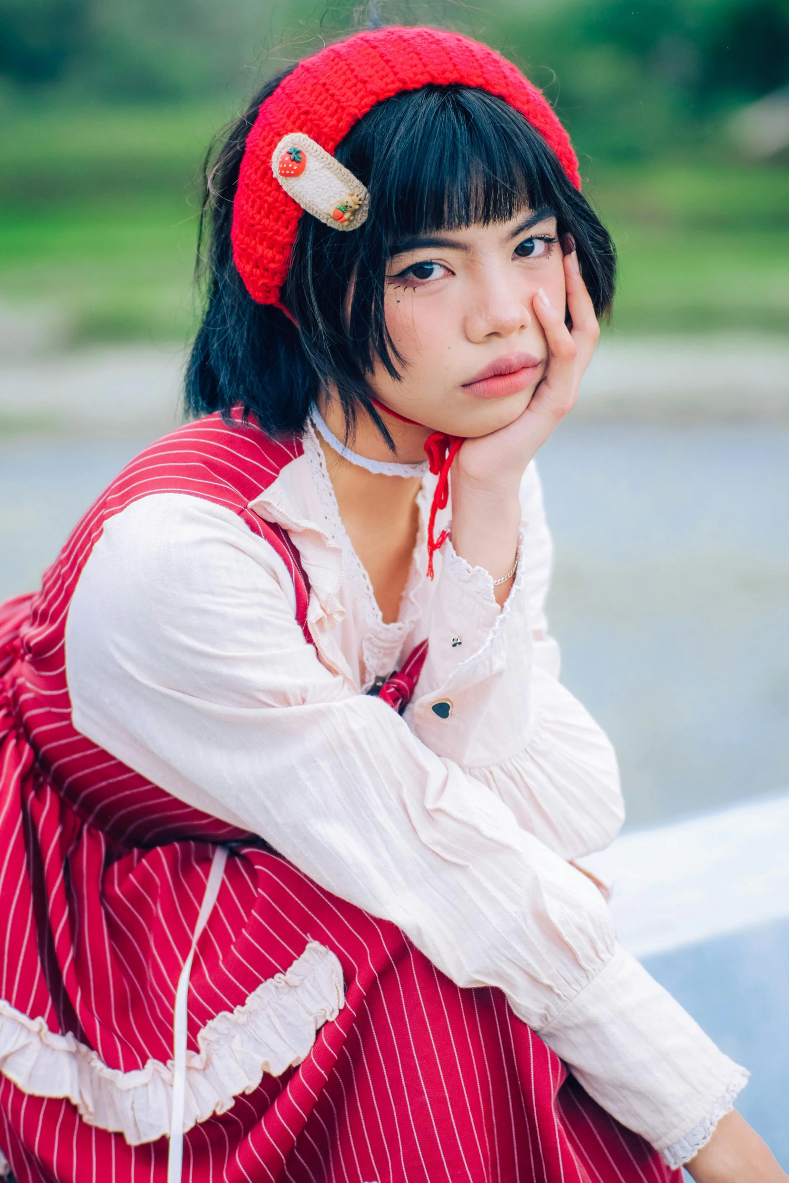 a woman in a red dress and hat with a cat on her head