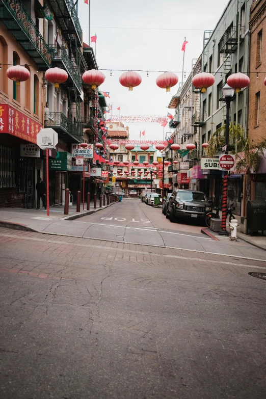 an empty street with chinese lanterns hanging over it