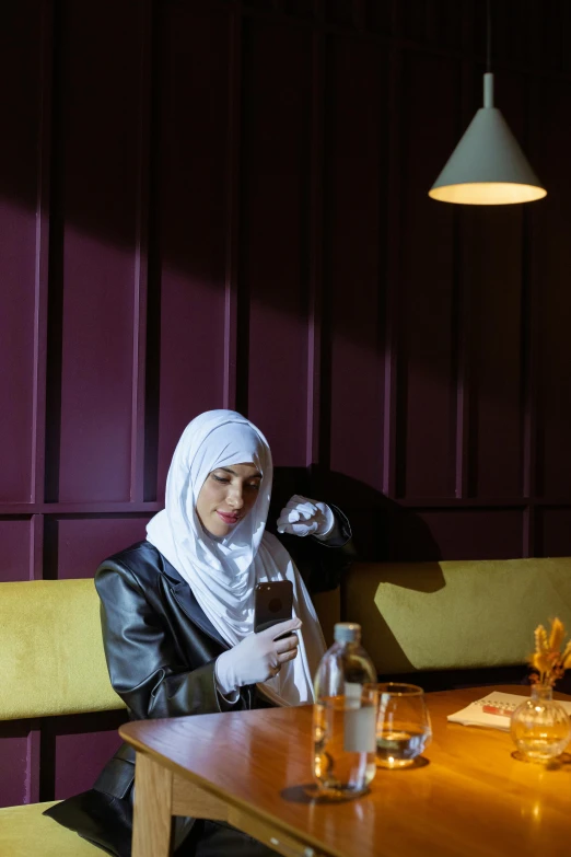 a woman sitting in a booth on her phone