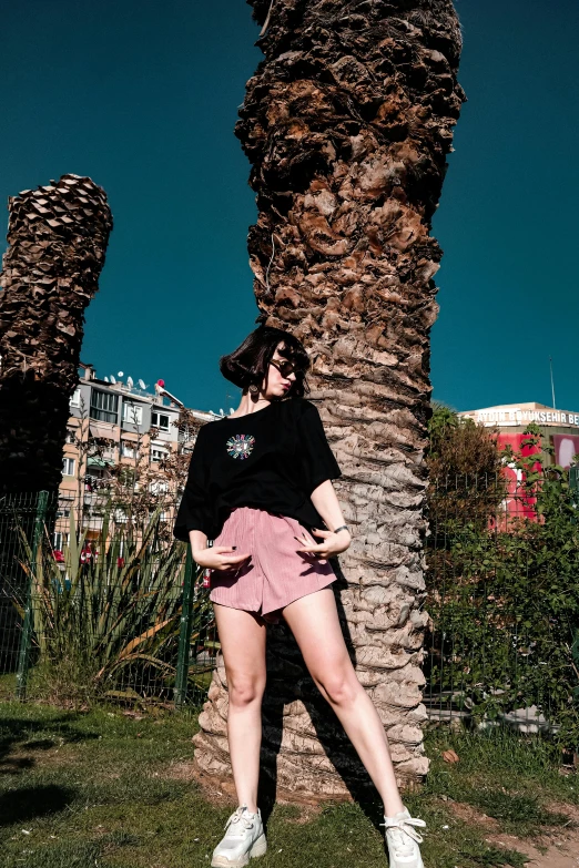 woman posing with her leg up against a palm tree