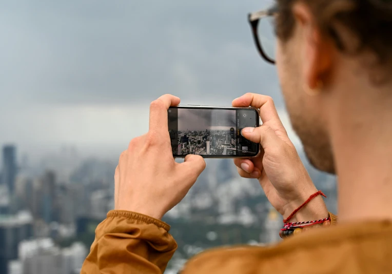 a man in brown holding up a cell phone taking a po