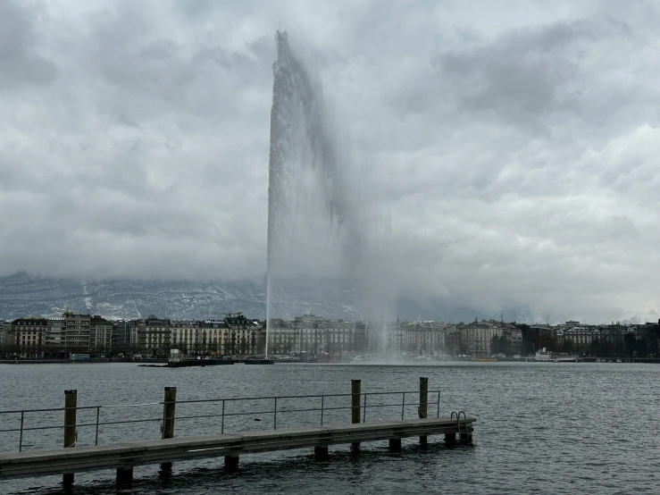 a water fountain in the foreground with dark clouds