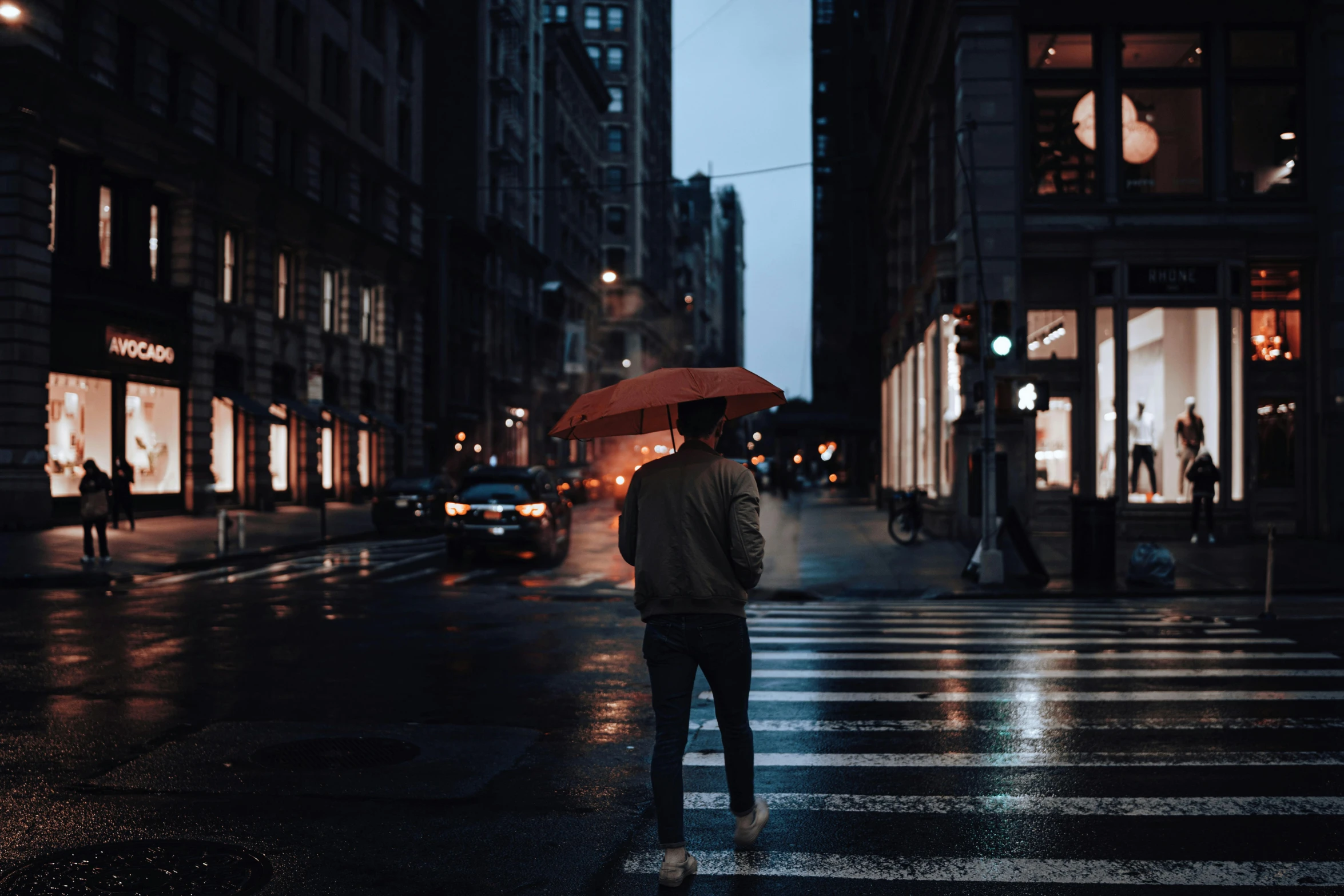 a man is standing on the street in the rain holding an umbrella