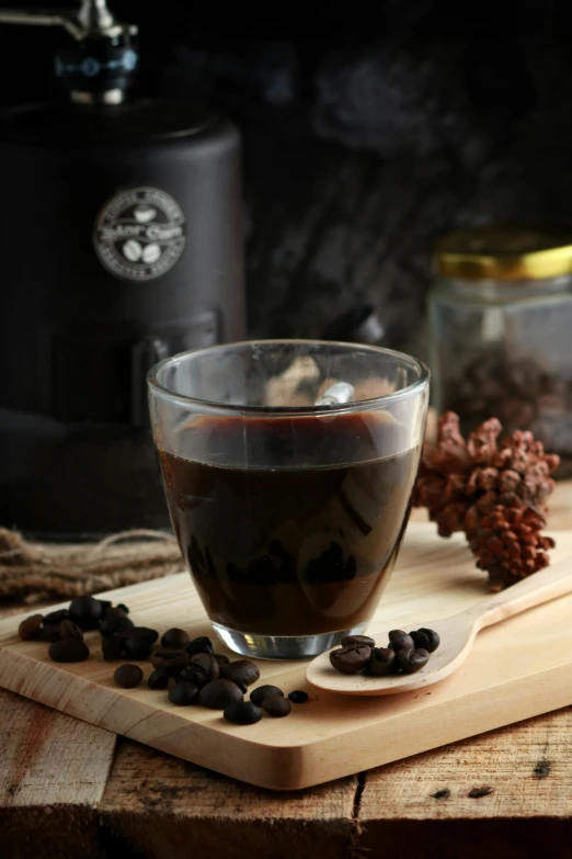 a glass cup filled with liquid surrounded by beans and coffee beans