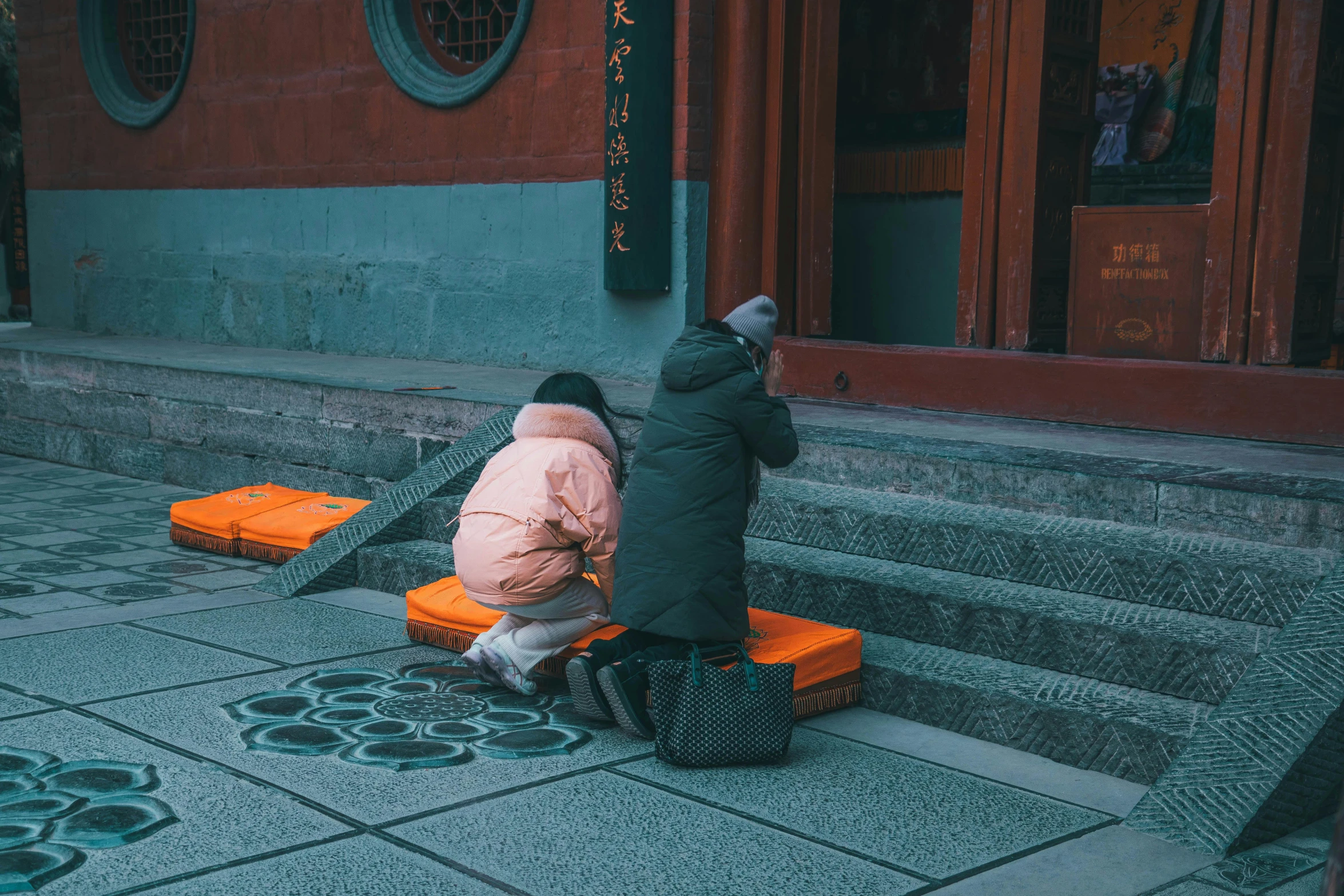 two people sitting on a bench, one in a pink jacket