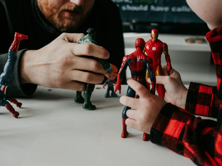 two children hold their hands over figurines on a table