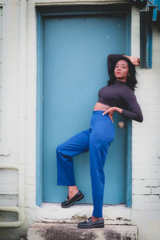 a woman in black top leaning on blue wall