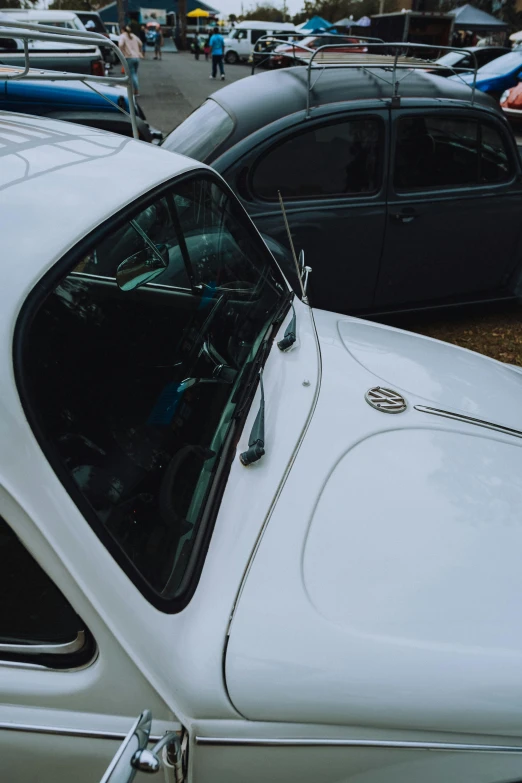 white car parked on parking lot with people standing nearby