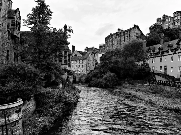 an old river runs down between buildings under cloudy skies