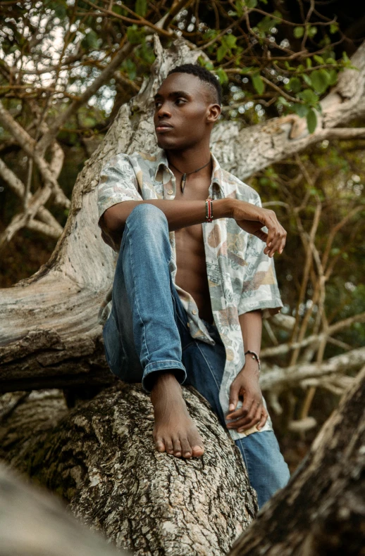 a young man sits on a rock with his shirt over