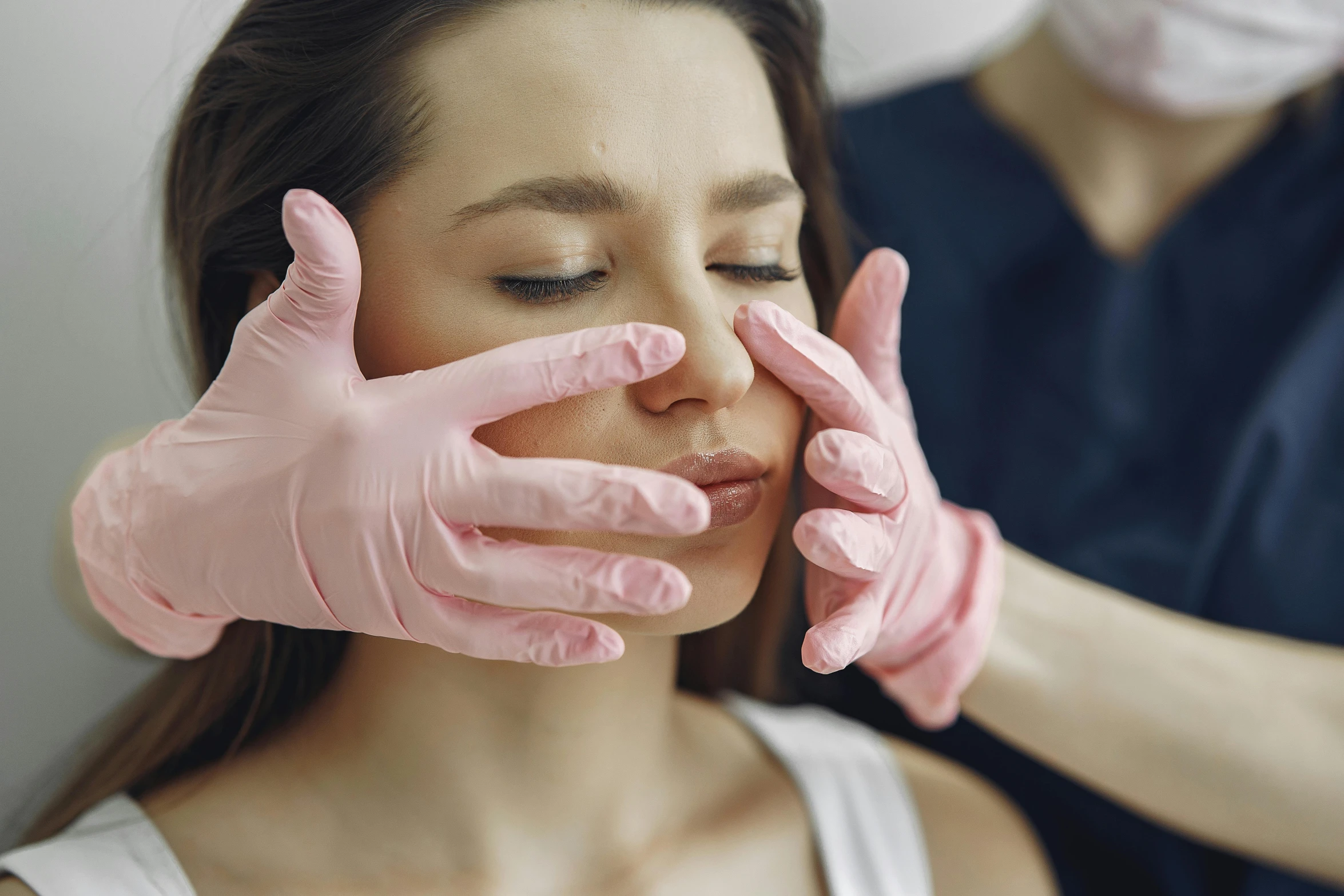 a lady wearing pink gloves is giving a medical help