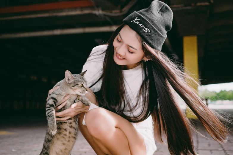 a woman holding a gray kitten in her hands