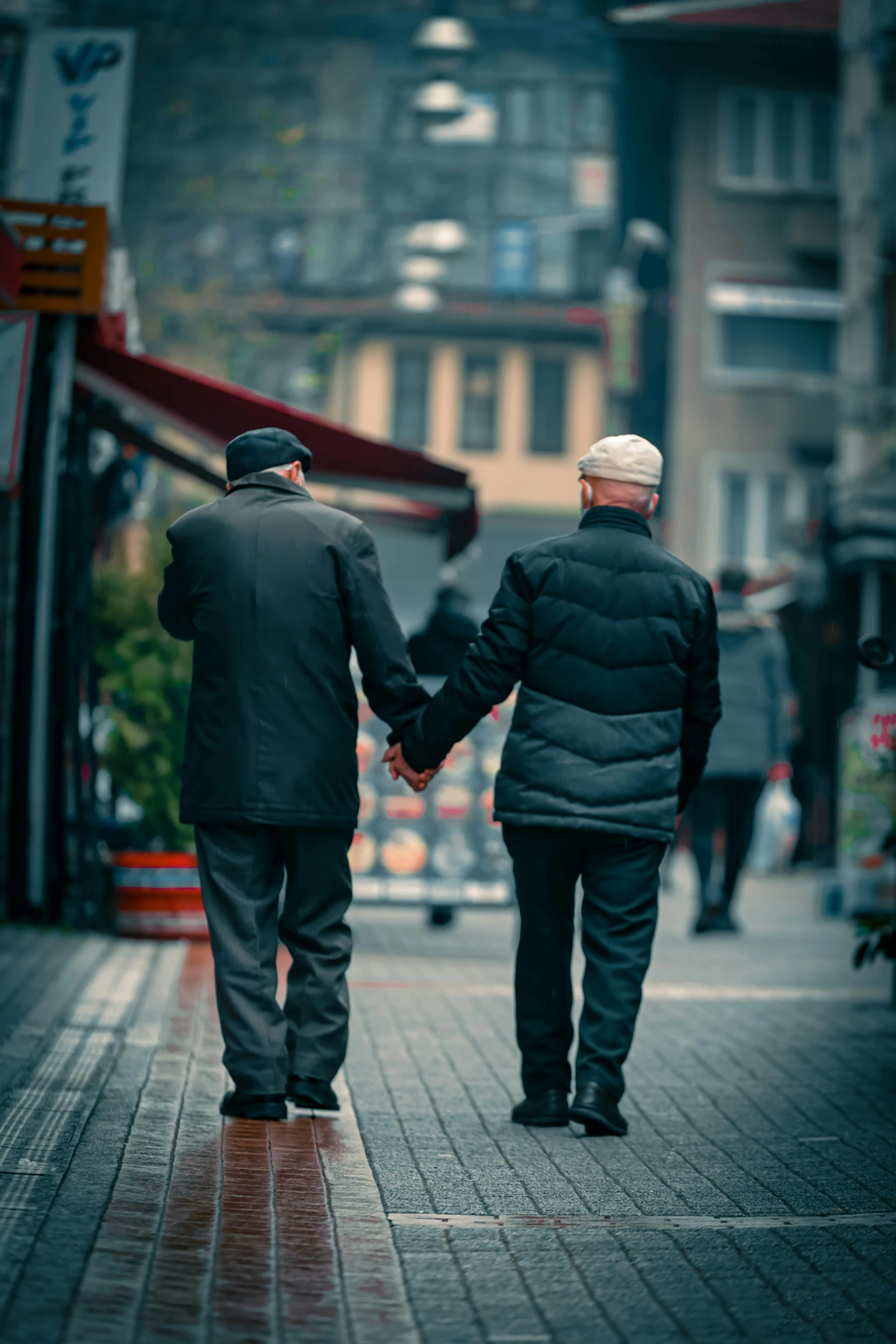 an older couple walks down the sidewalk holding hands