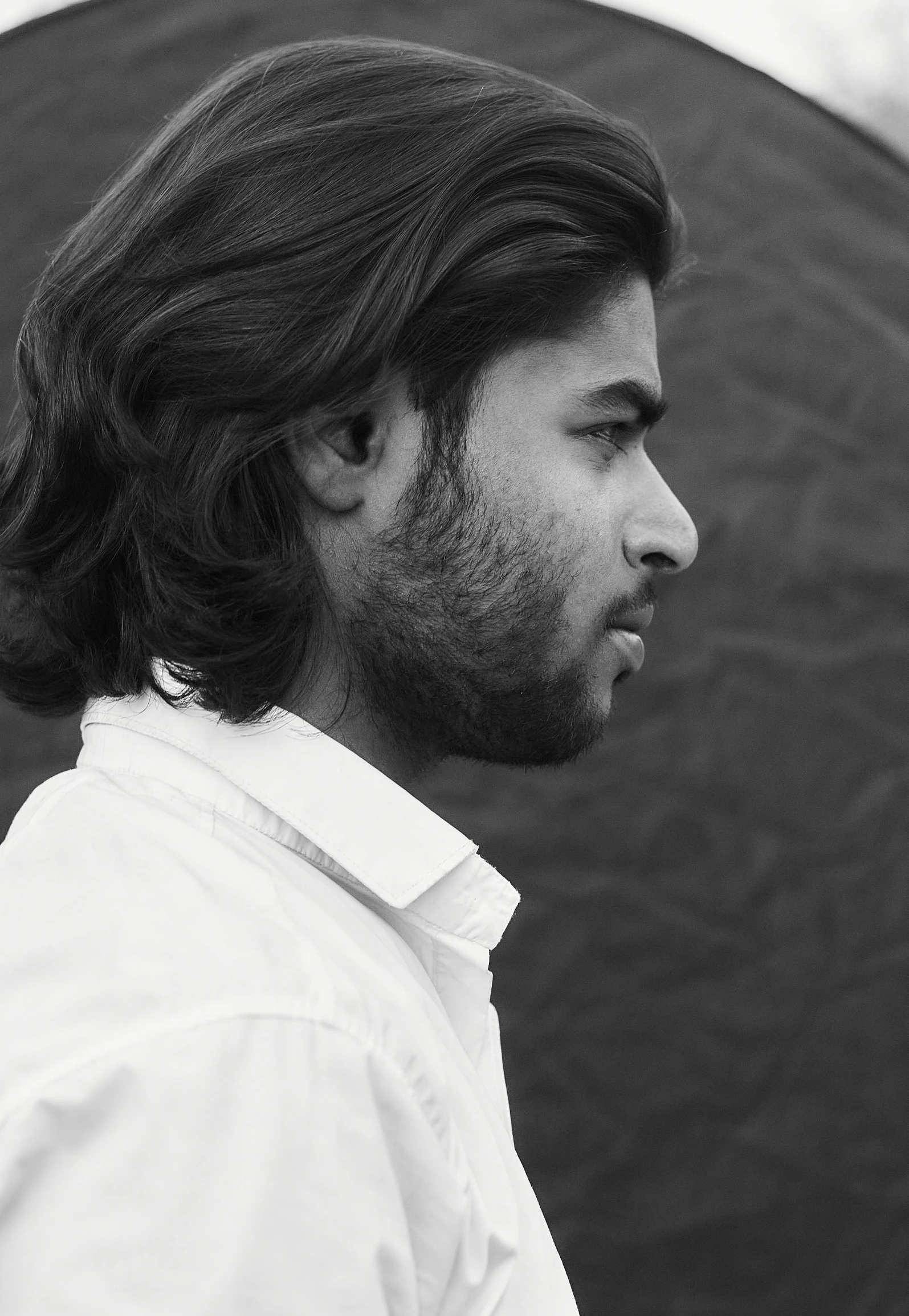 a man with long hair and a white on up shirt in front of an umbrella