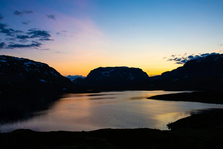 an image of water and mountains at sunset