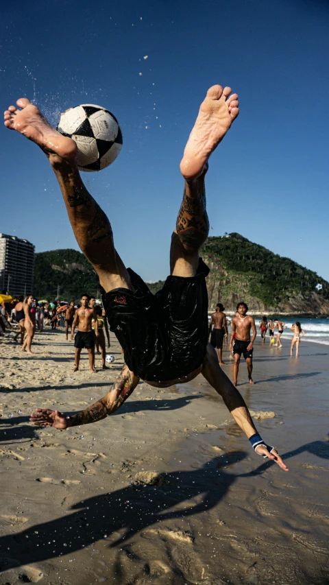 the man is playing soccer on the beach