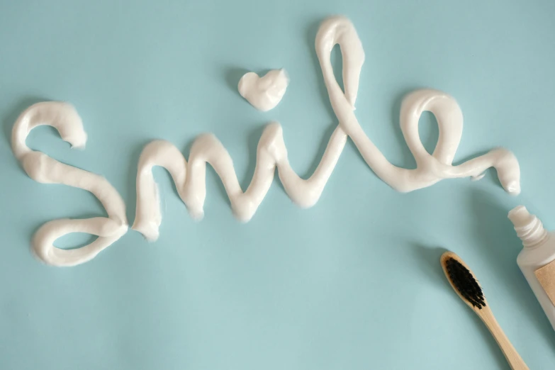a toothbrush next to the word smile made of whipped cream