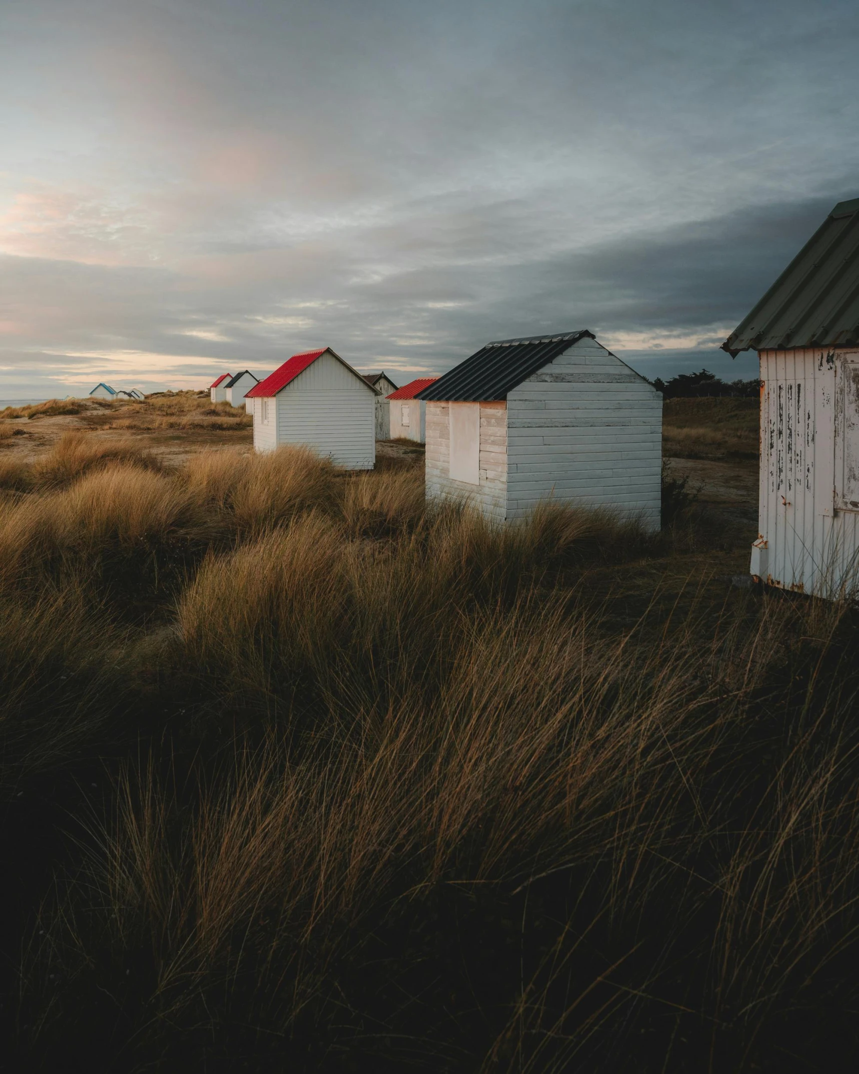 two small white houses on grass in the middle of a field